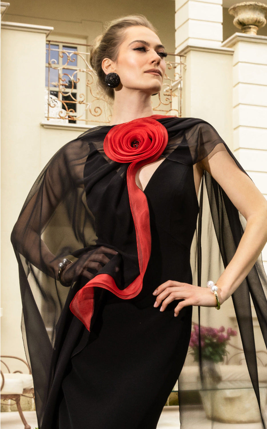 Abito lungo nero con mantella in chiffon e rosa scultorea rossa